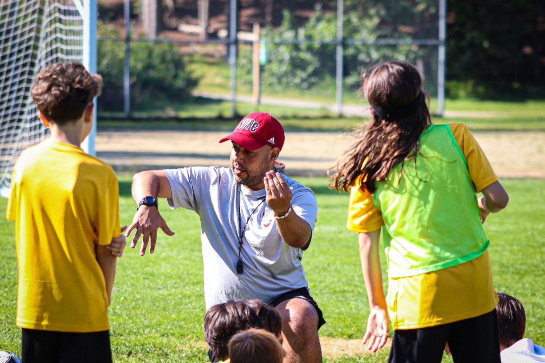 A coach demonstrating to players on the grass